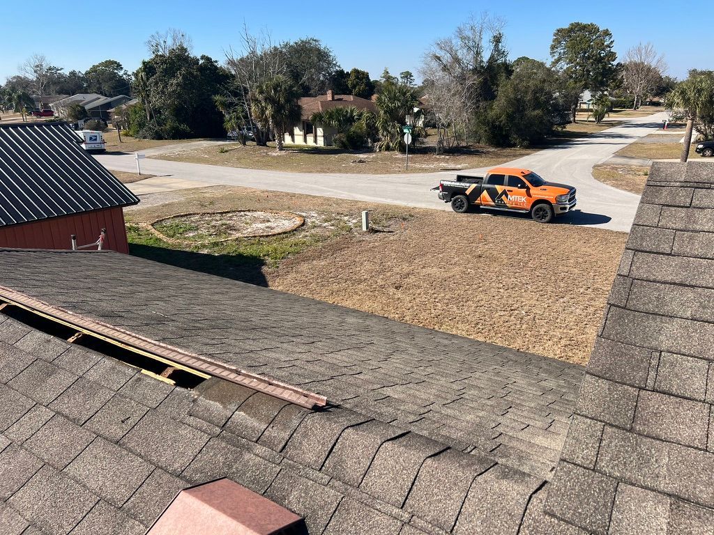 Person laying bricks atop a low wall outdoors under a clear sky