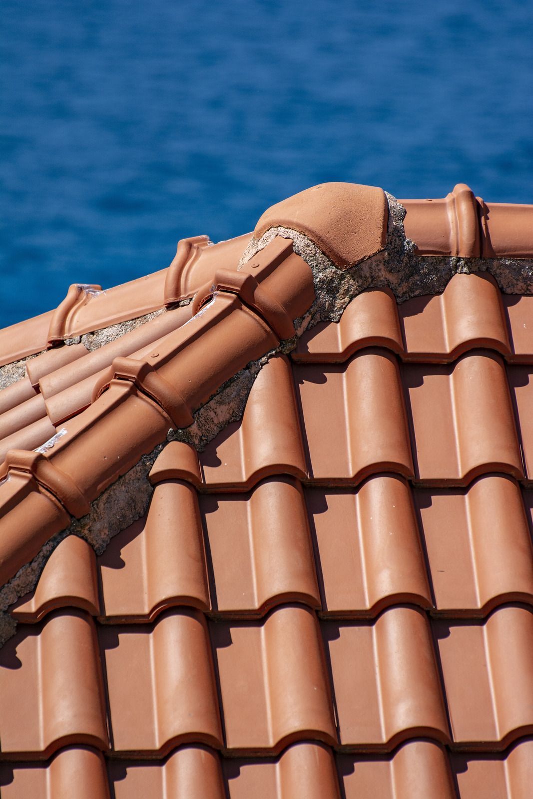 Terracotta roof tiles with a blue sea in the background