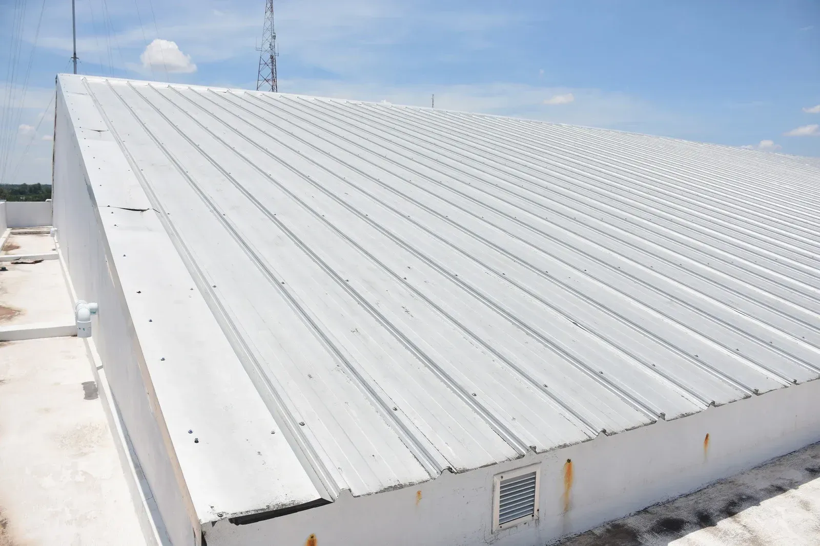 White corrugated metal roof on a low industrial building under a blue sky