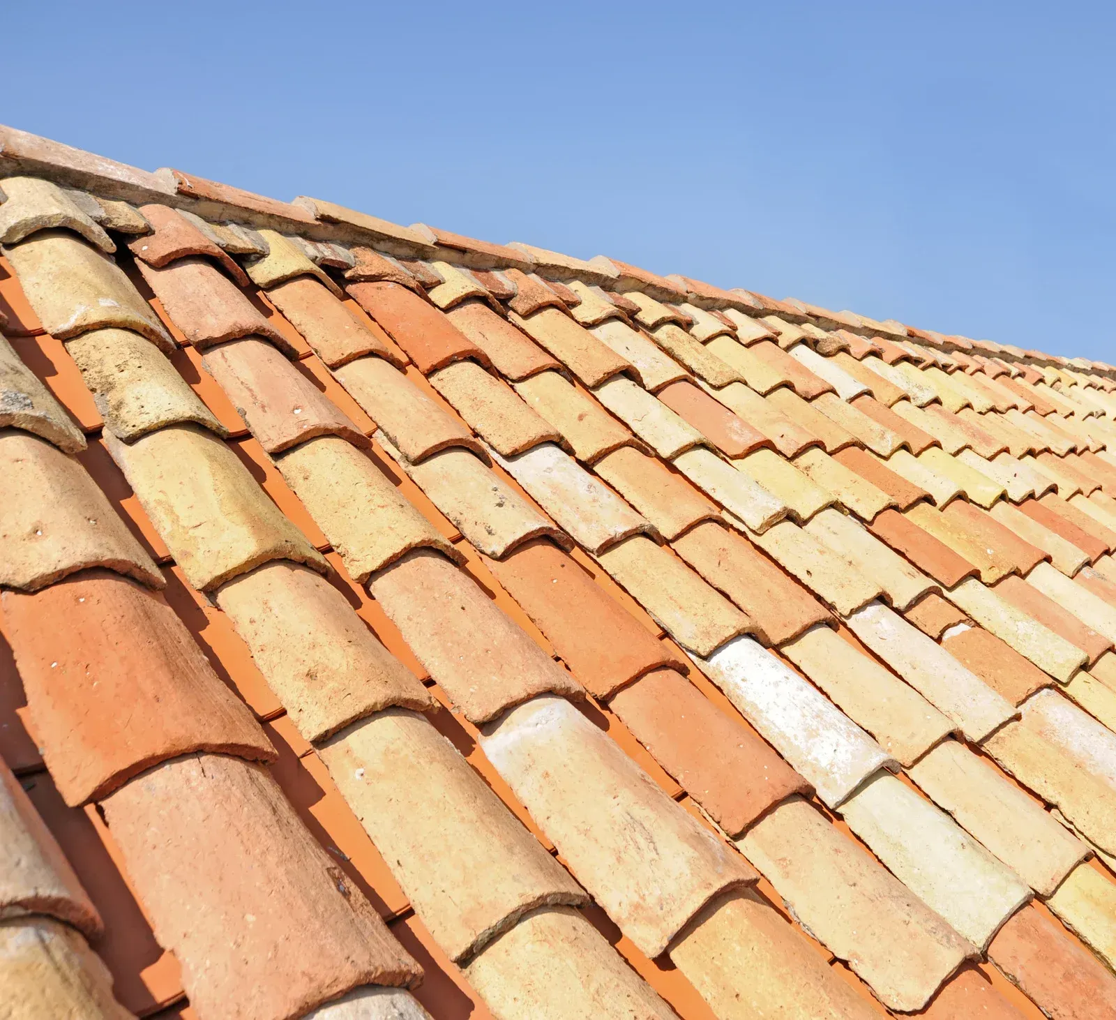 Sunlit terracotta roof tiles against a clear blue sky