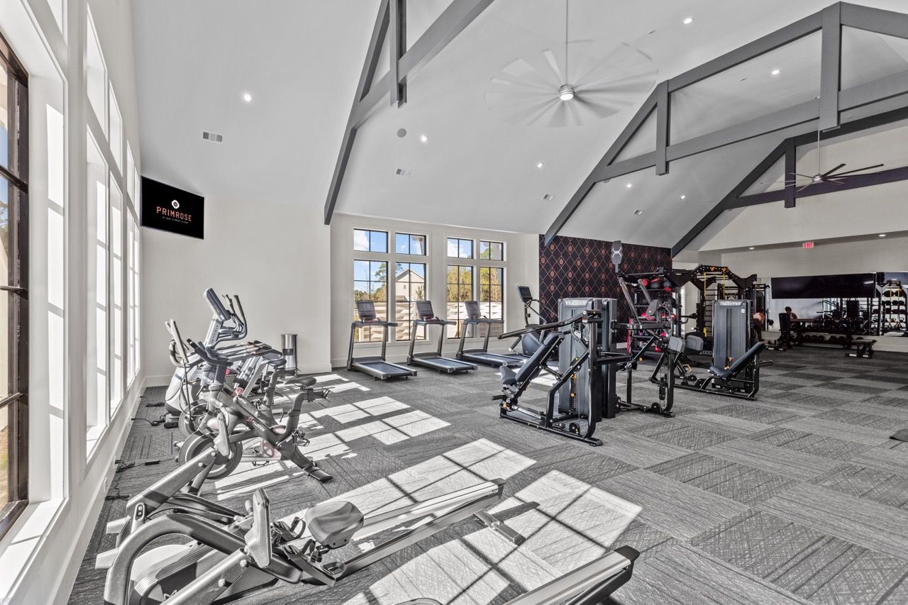 Bright fitness center with cardio machines, treadmills, and weight machines.