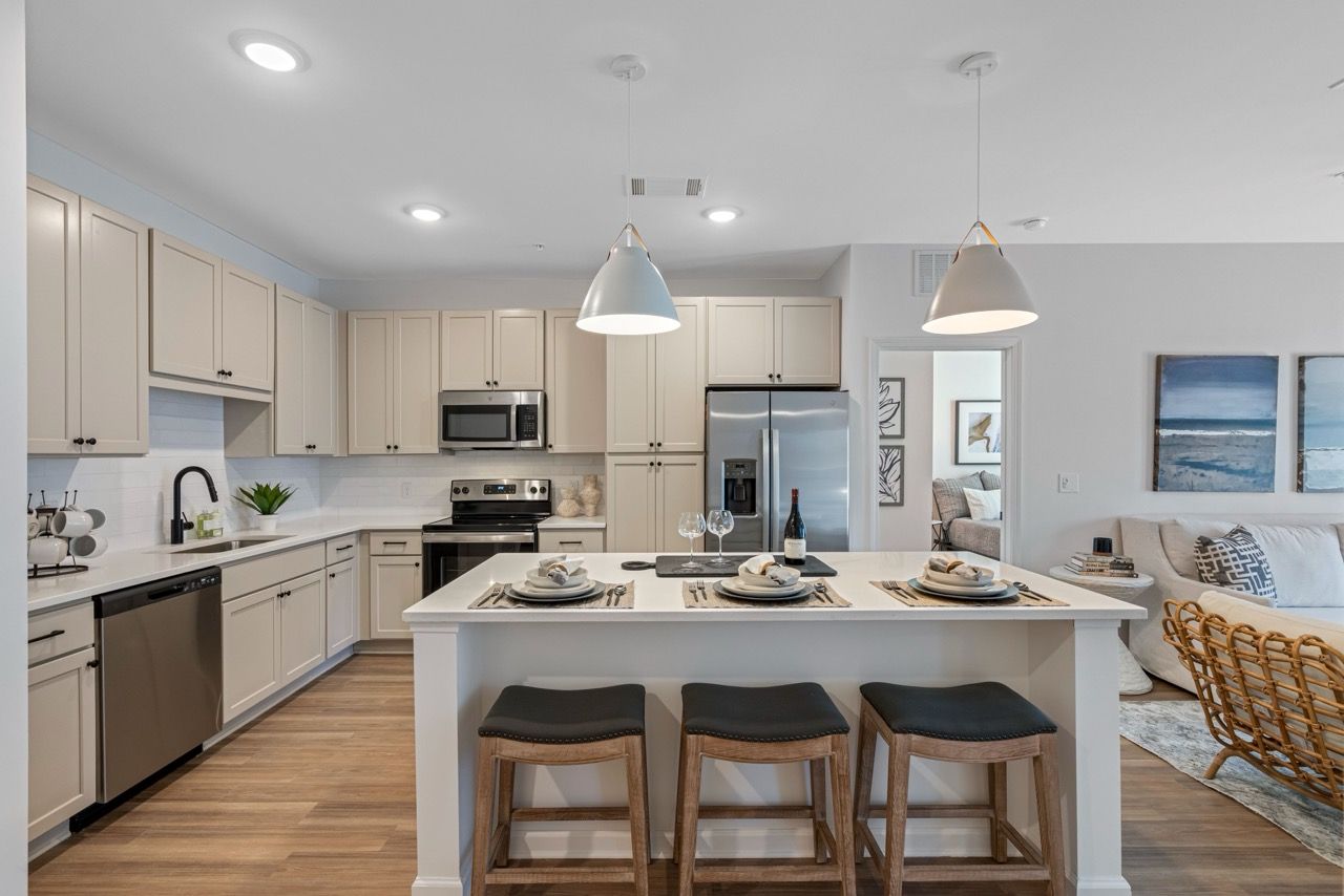 Open-concept kitchen with white cabinets, island seating, and stainless-steel appliances.