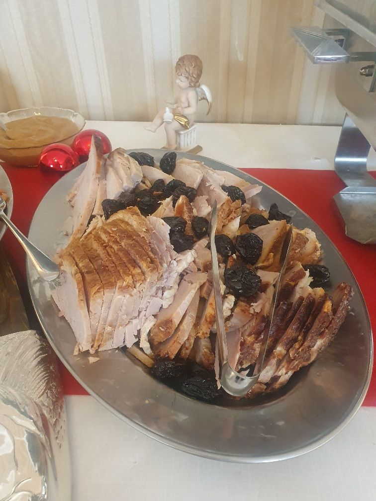 A plate of meat with raisins and tongs on a table.