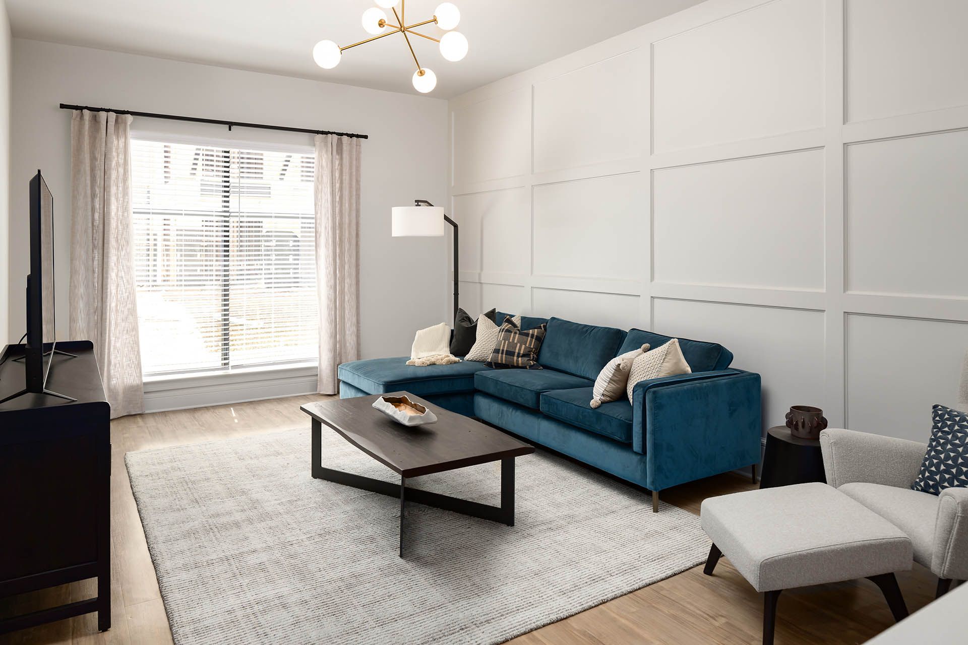 A living room with a blue sectional couch , coffee table , chair and television.