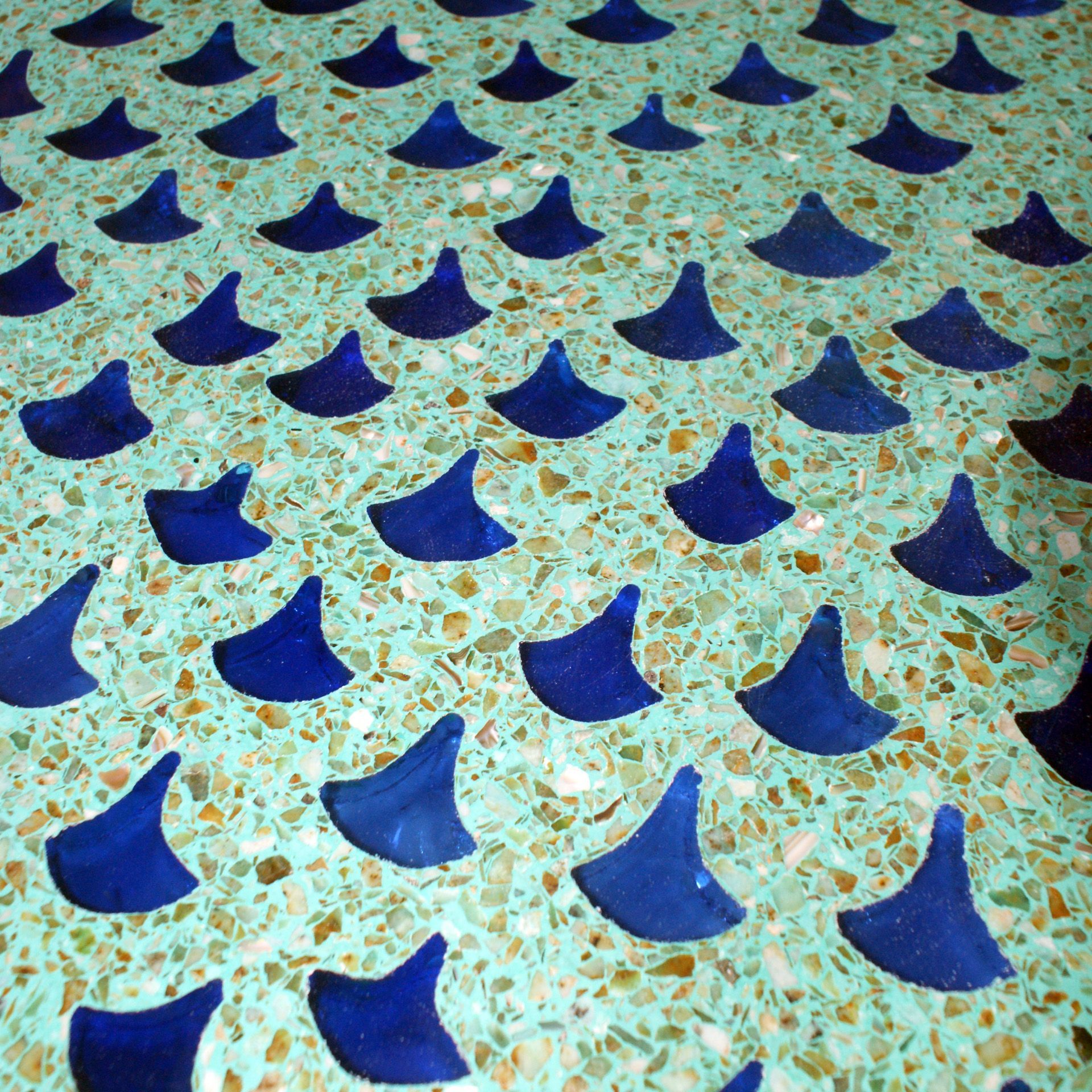 A pattern of blue shark fin shaped tiles on a green surface