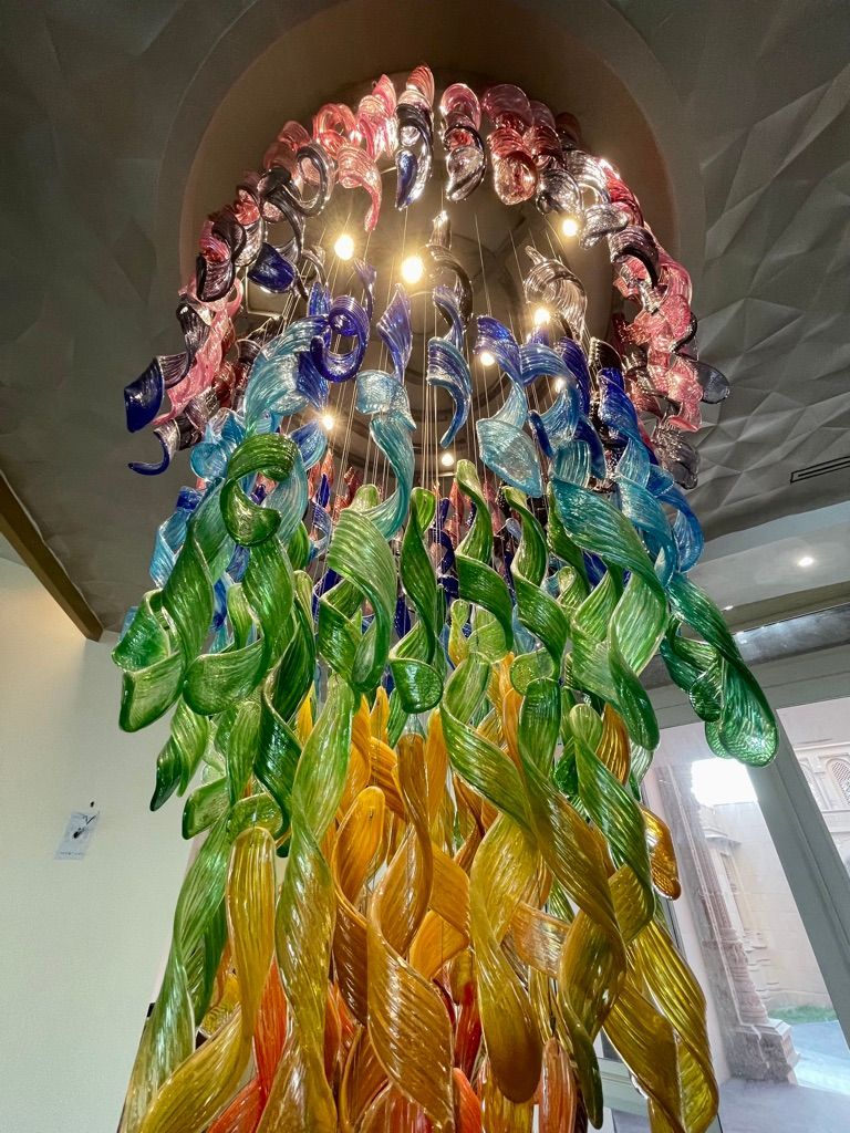 A chandelier made of glass flowers and leaves is hanging from the ceiling.