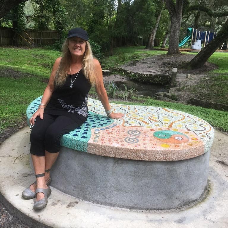 A woman is sitting on a colorful bench in a park
