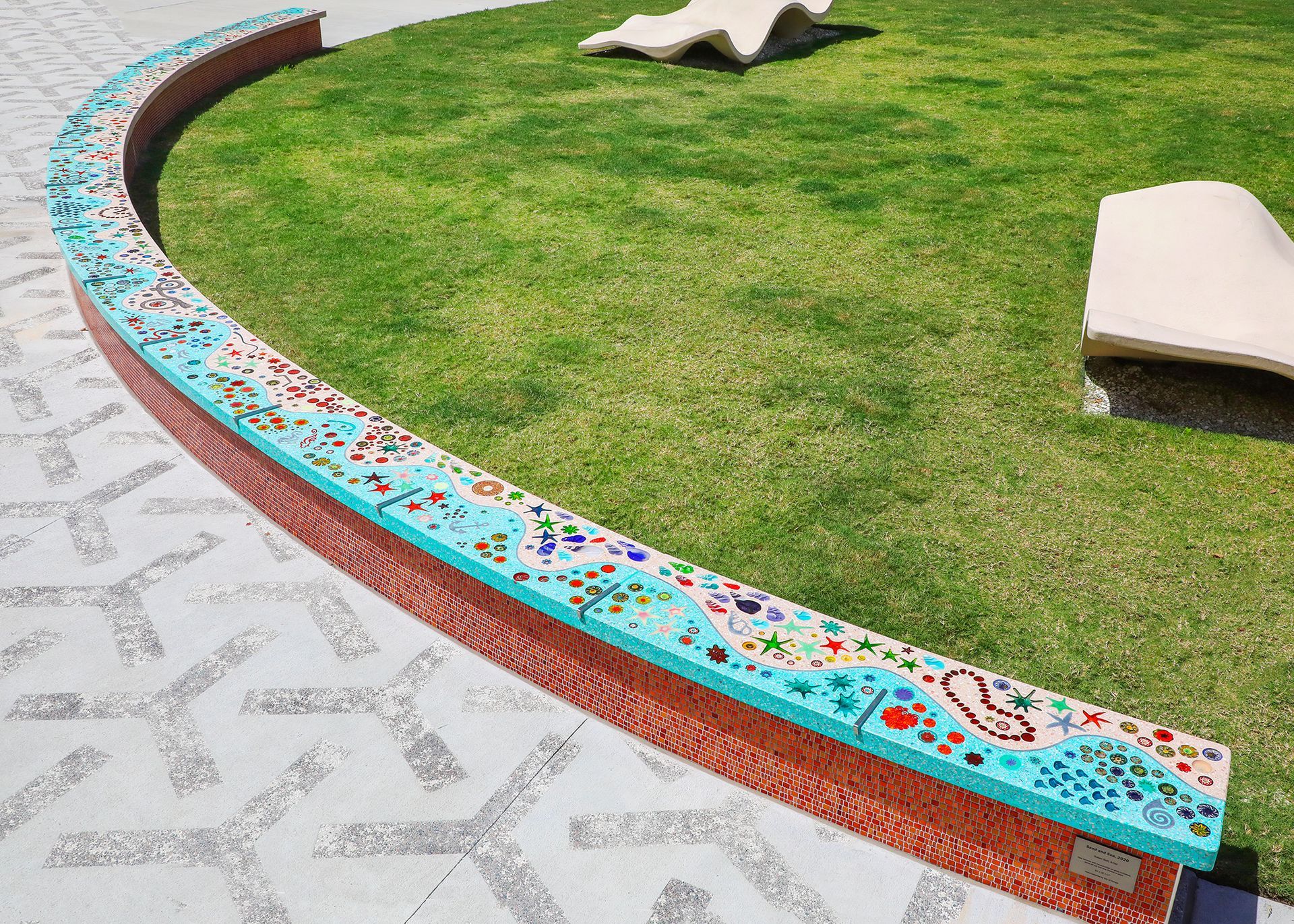 A colorful bench is sitting in the middle of a lush green field.