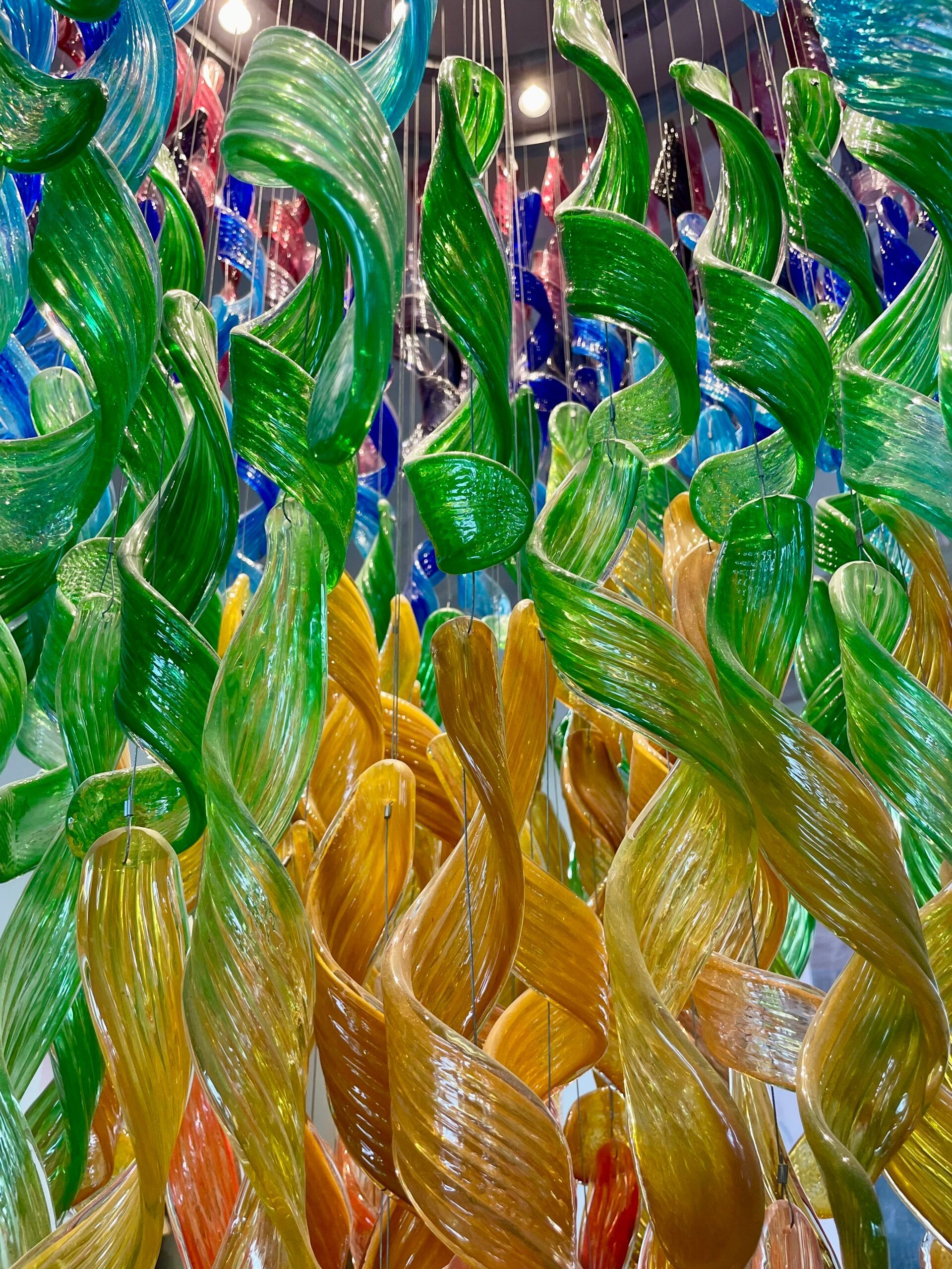 A bunch of colorful glass sculptures are hanging from the ceiling.