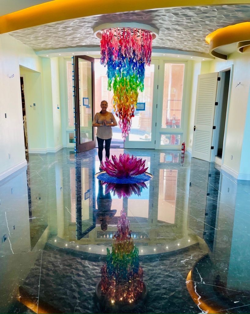 A woman is standing in a hallway with a chandelier hanging from the ceiling.