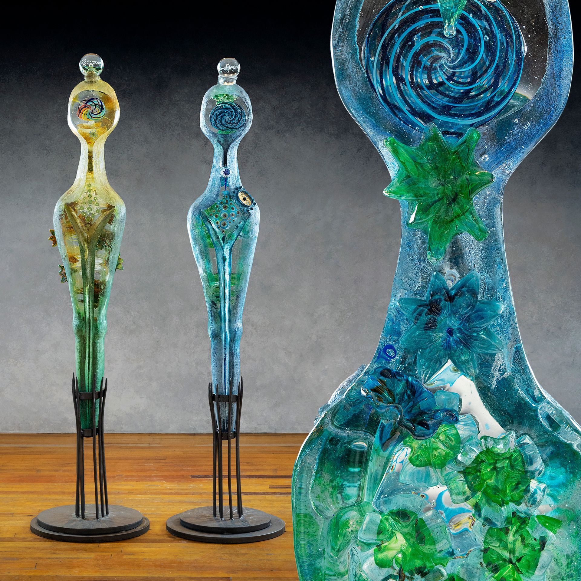 Three glass sculptures are sitting on a wooden table