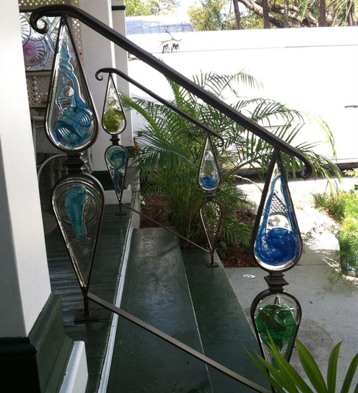 A staircase with a glass railing with blue and green drops hanging from it