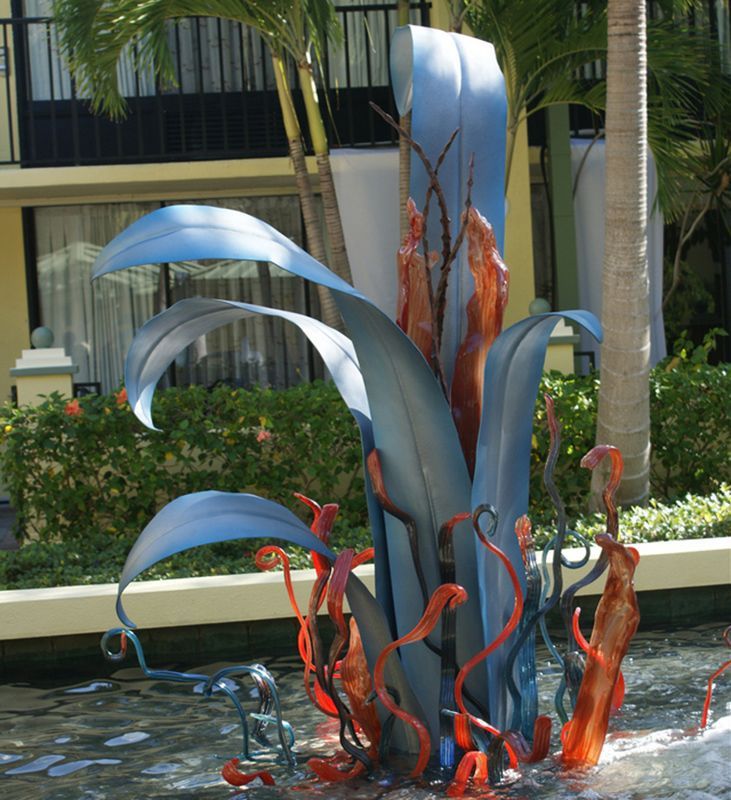 A sculpture of a plant with blue leaves and red flowers
