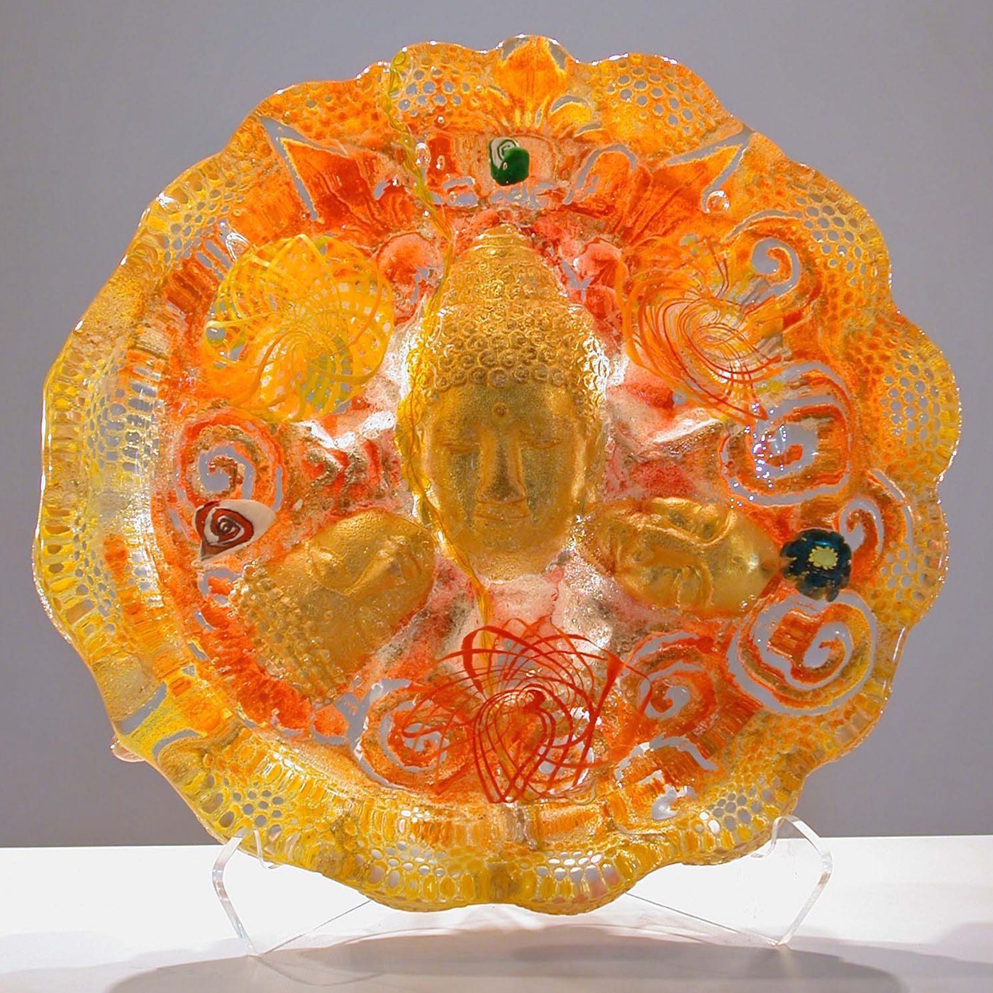 A yellow and orange plate is sitting on a clear stand