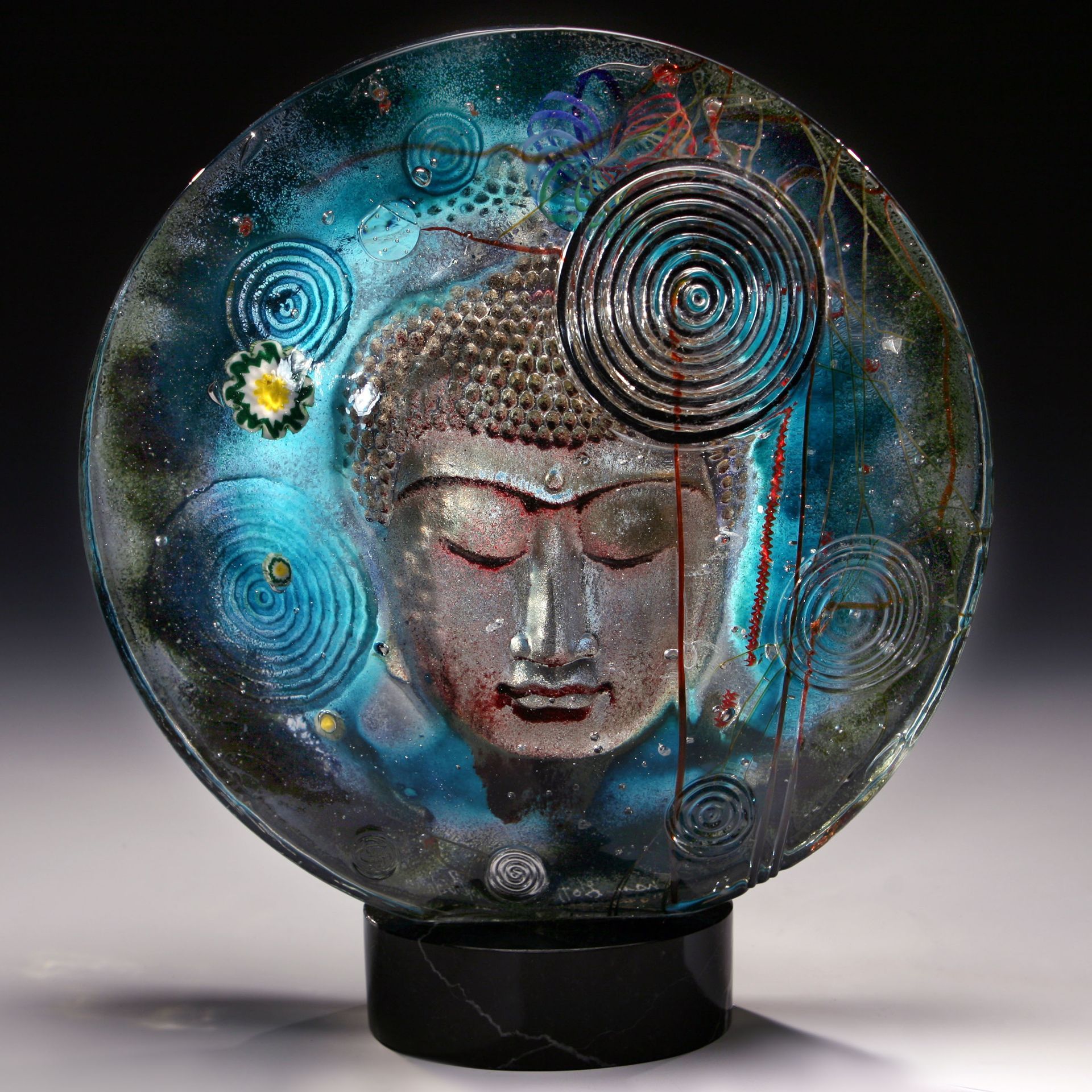 Glass sculpture: Buddha face within a blue, cosmic background, mounted on a black base.