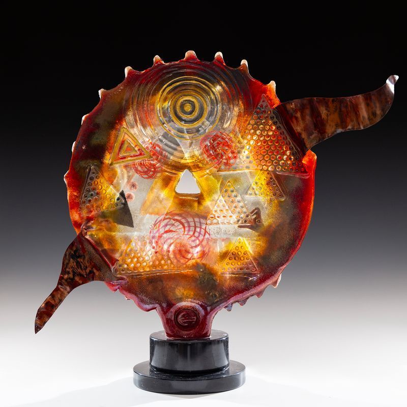 A red glass sculpture with a black base is sitting on a table