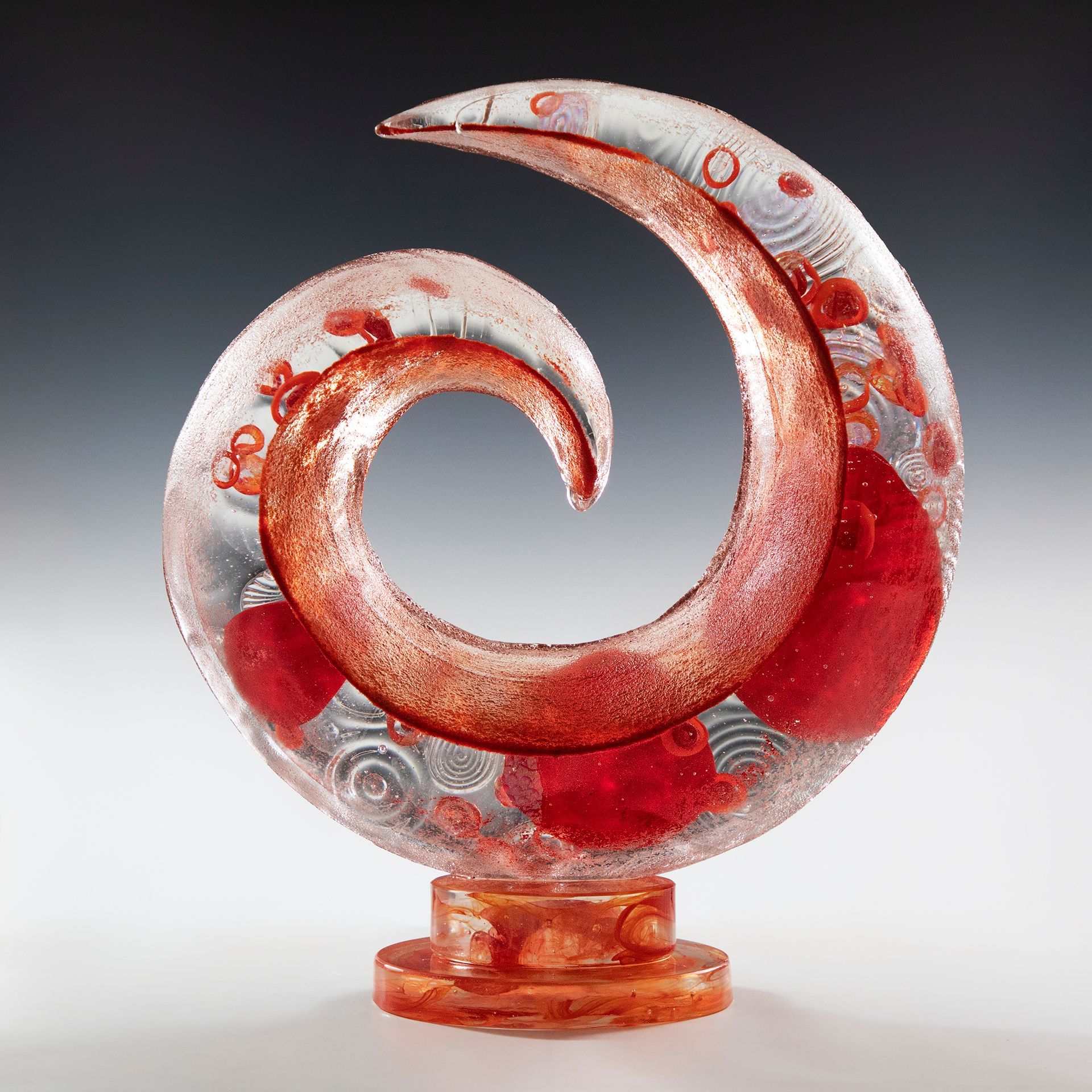 A glass sculpture with a red swirl in the middle