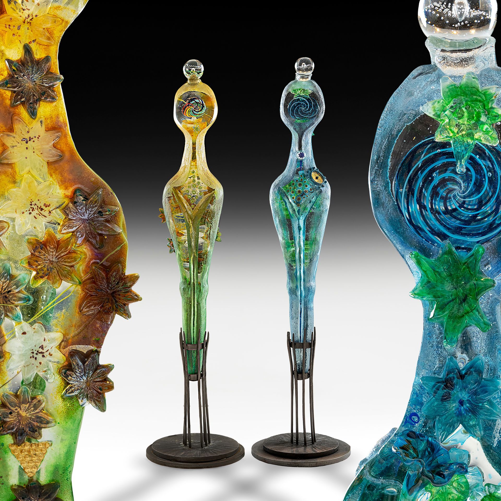 Three different colored glass sculptures are sitting next to each other