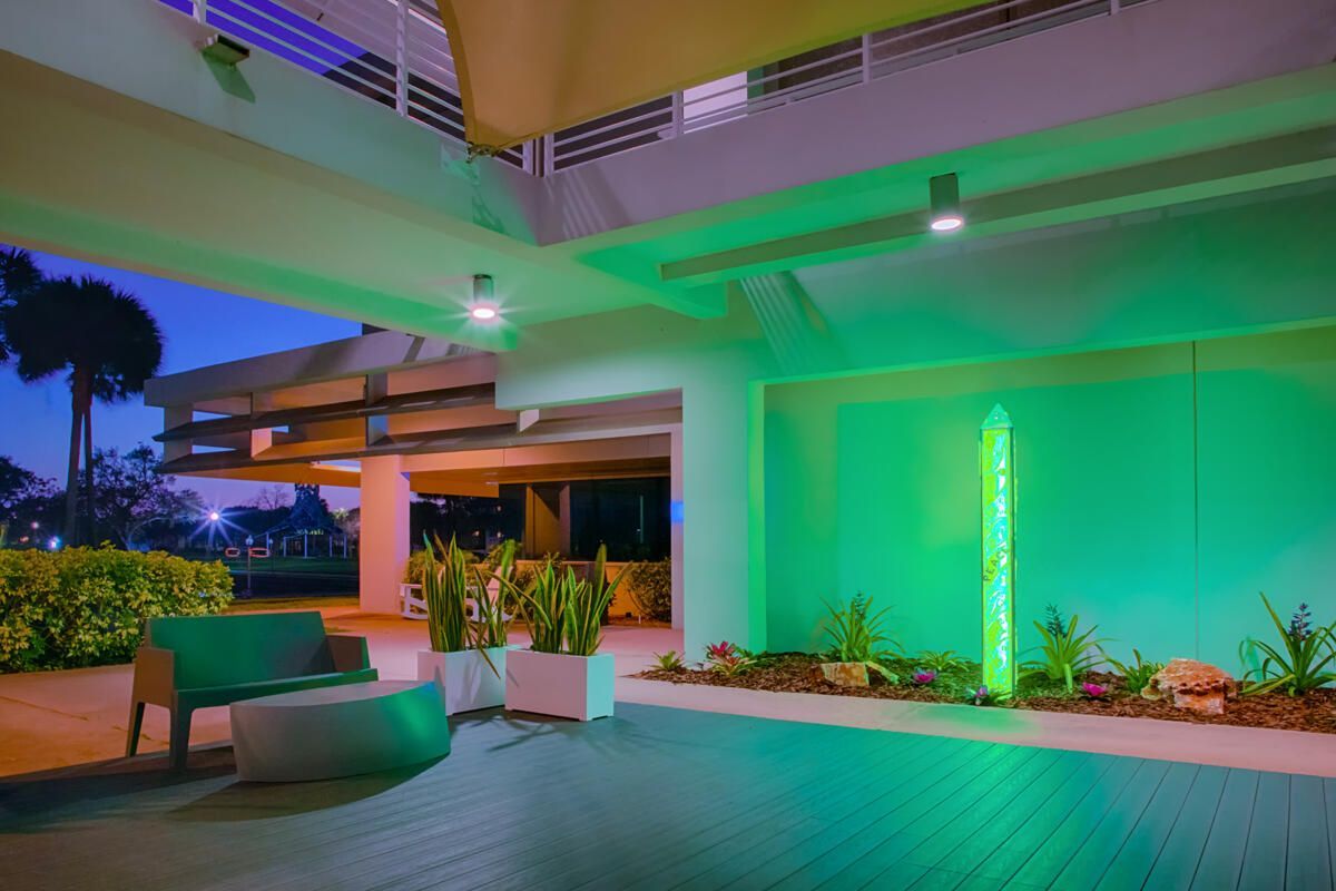 There is a bench in the middle of the room with green lights on the walls.