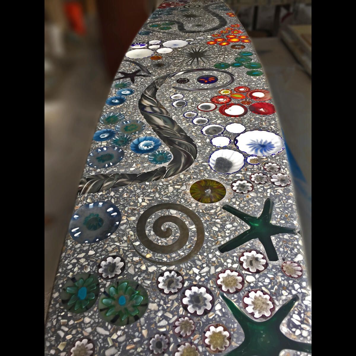 A mosaic table with flowers swirls and starfish on it
