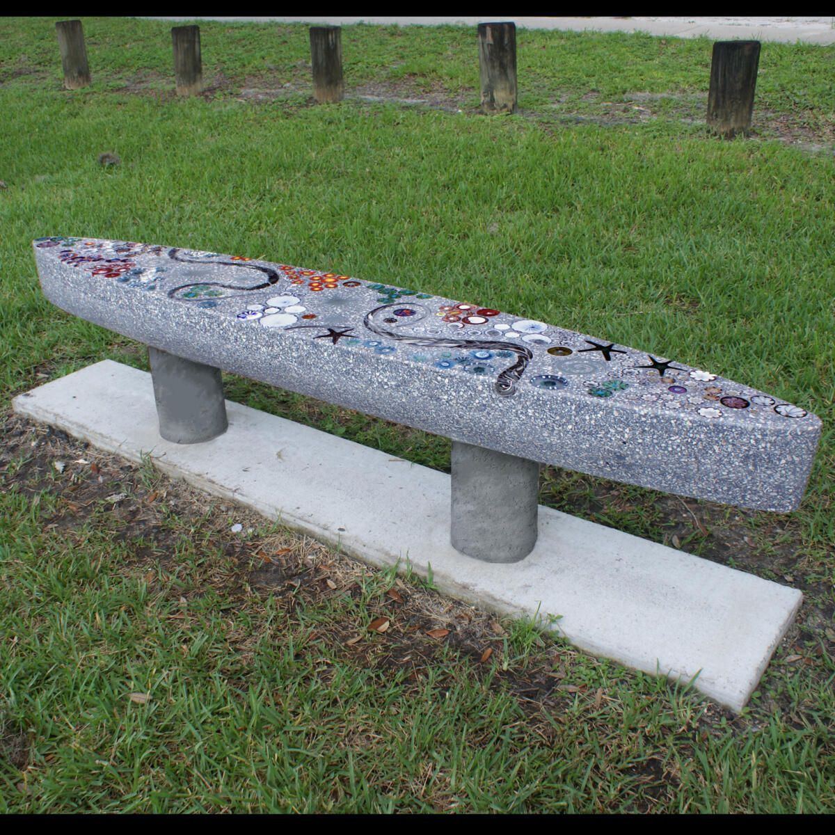 A concrete bench is sitting in the grass in a park