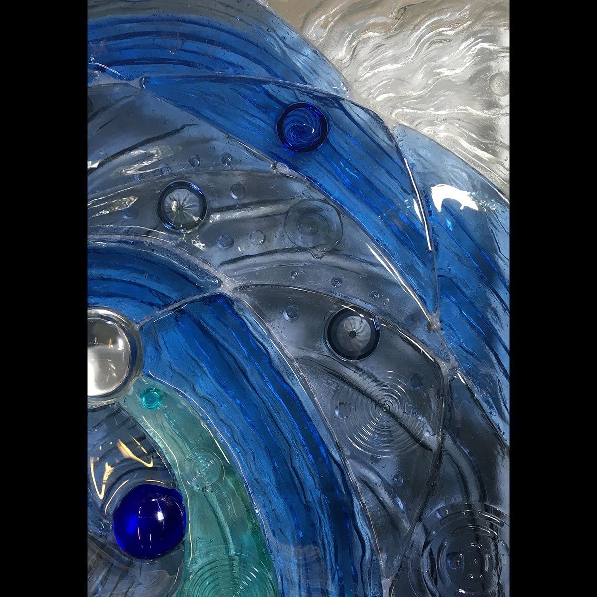 A close up of a glass sculpture with blue beads on it.