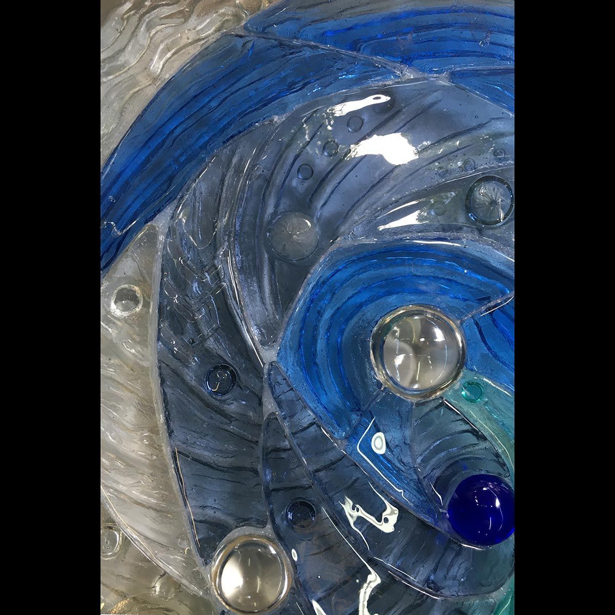 A close up of a blue and white mosaic with marbles.