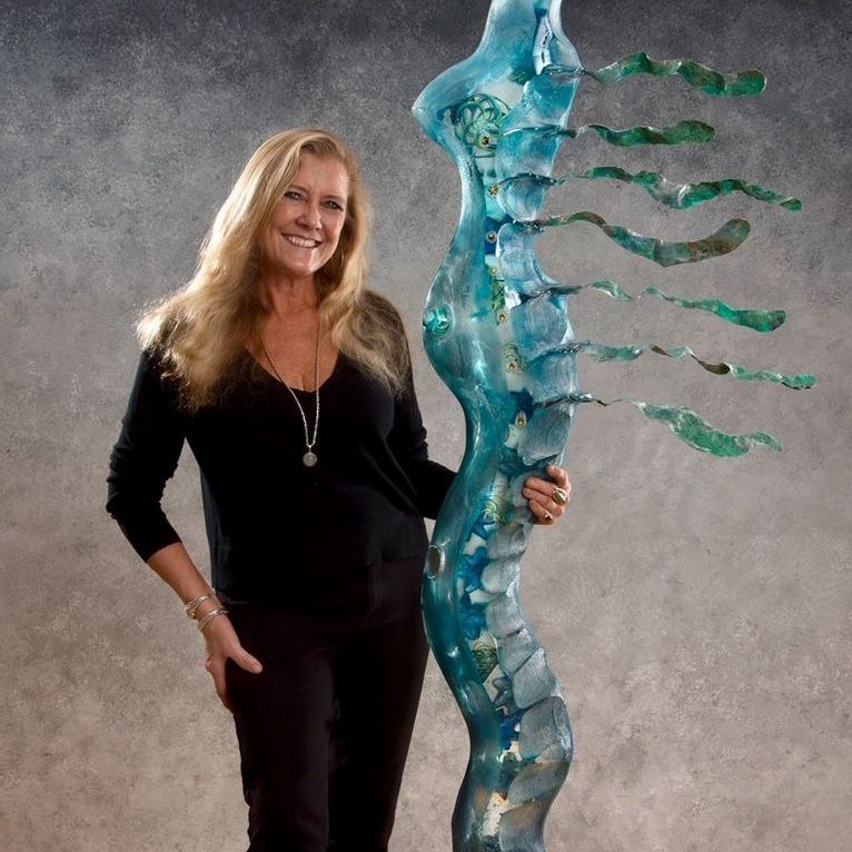 A woman is standing next to a large blue sculpture
