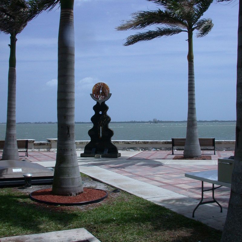 A park with palm trees and a table with a view of the ocean