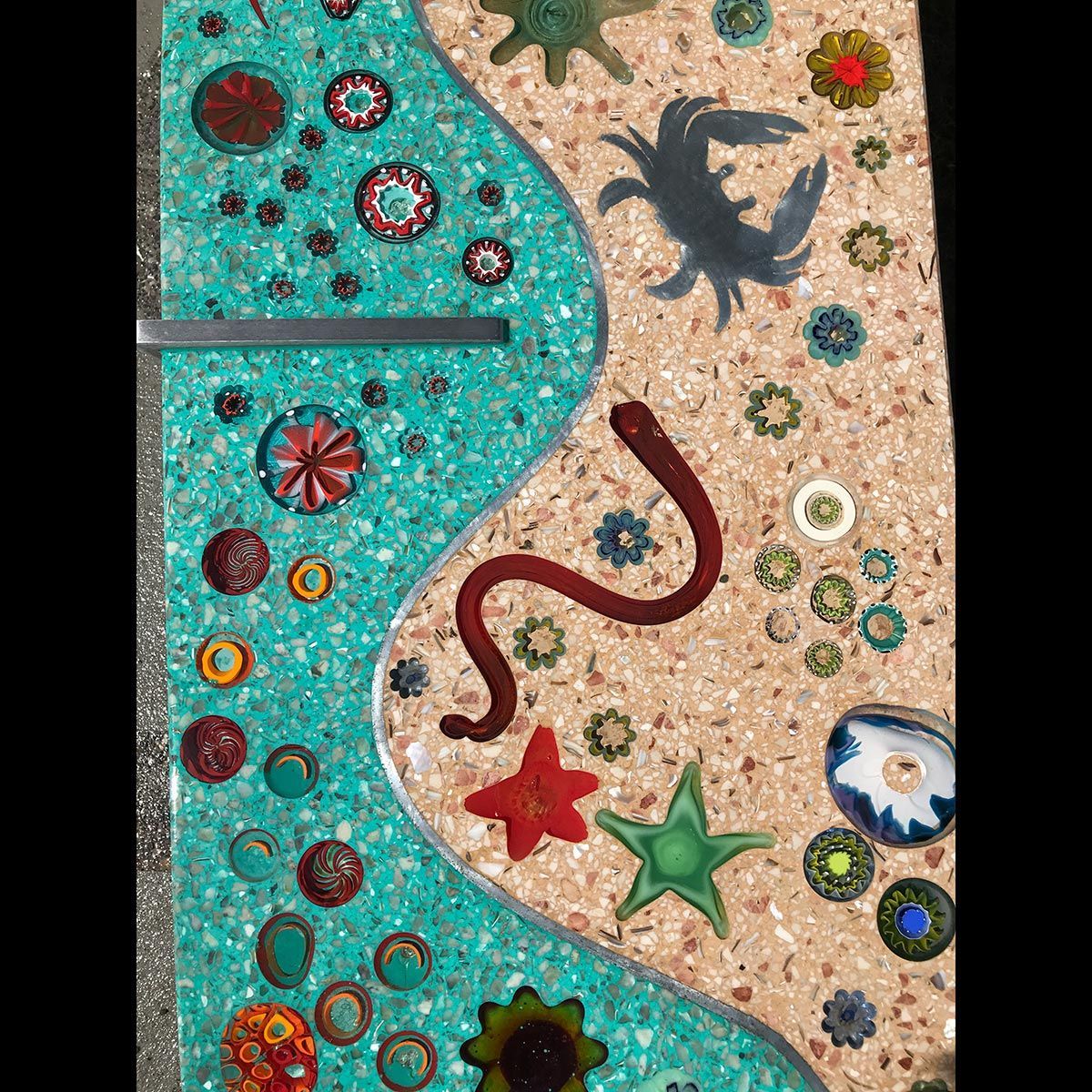 A mosaic of a river with a snake , starfish , crabs and flowers.
