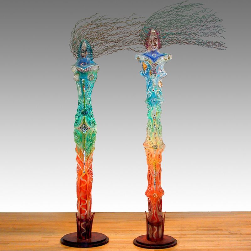 Two sculptures of a woman with long hair are sitting on a wooden table