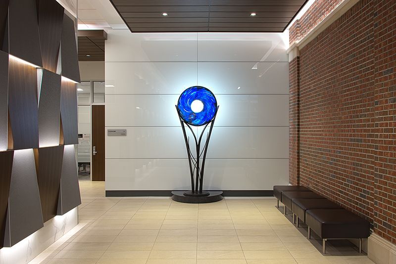 A large blue sculpture is sitting in a hallway next to a brick wall.