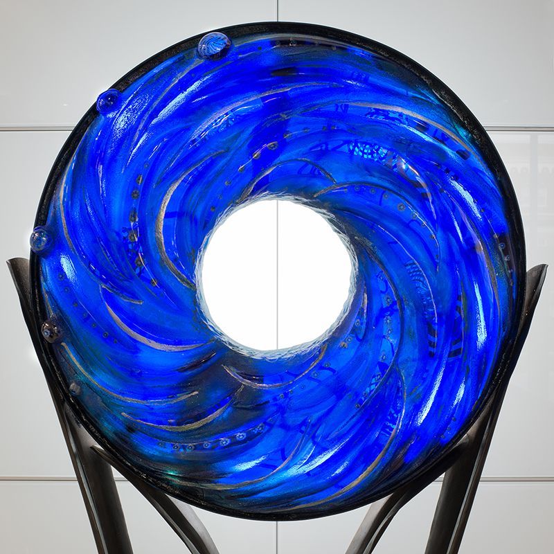 A blue glass sculpture with a hole in the middle