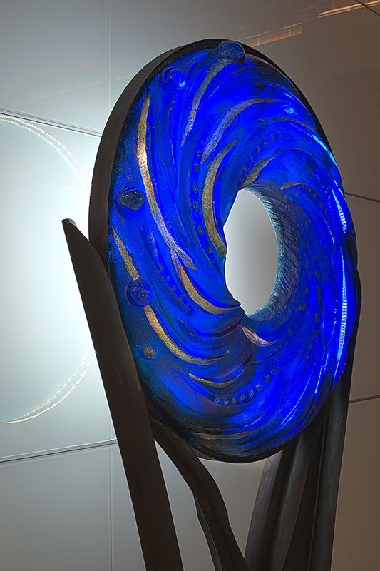 A blue sculpture with a hole in the middle is sitting on a table.