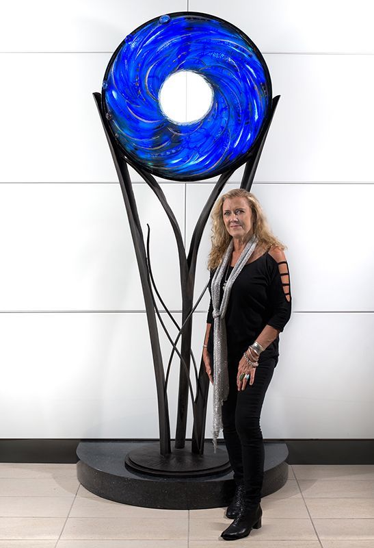 A woman is standing in front of a large blue sculpture.