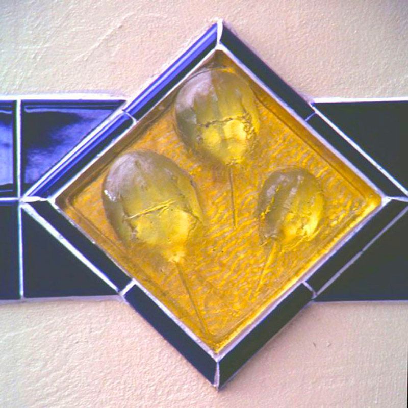 A stained glass square with three yellow balls in it