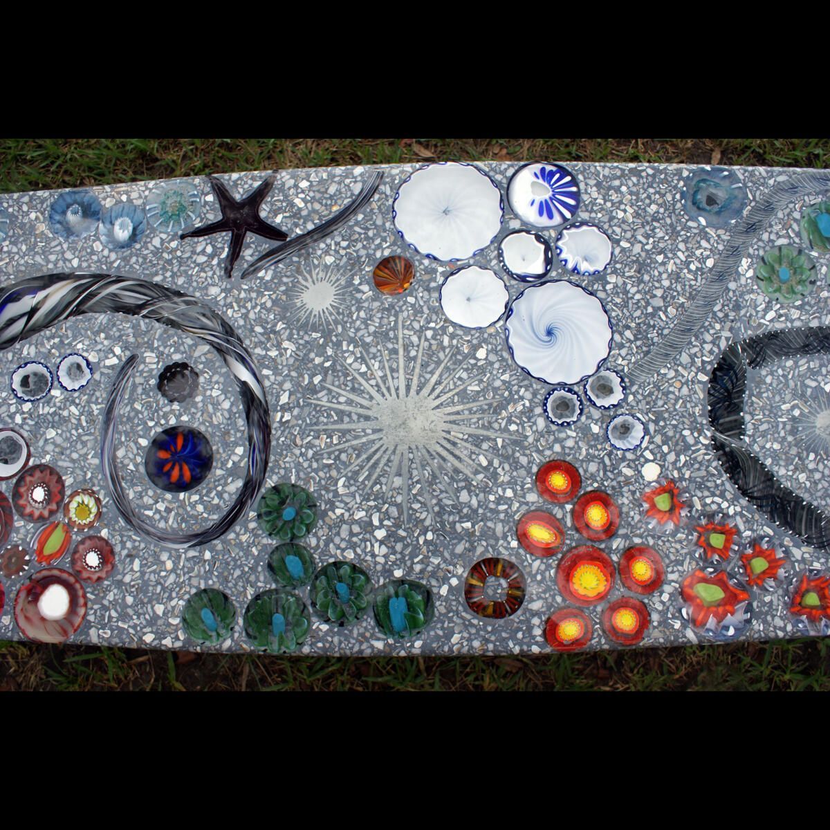 A painting of seashells and flowers on a concrete surface.