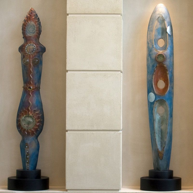 Two sculptures are displayed against a white wall