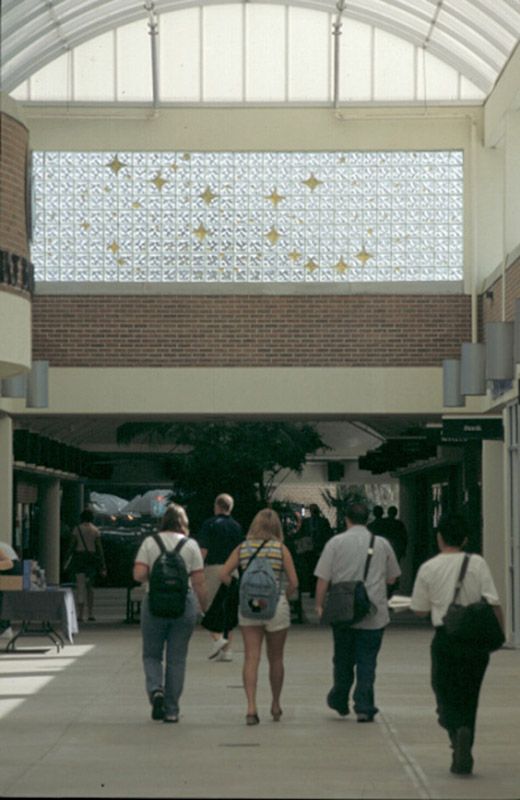 A group of people are walking down a hallway in a mall