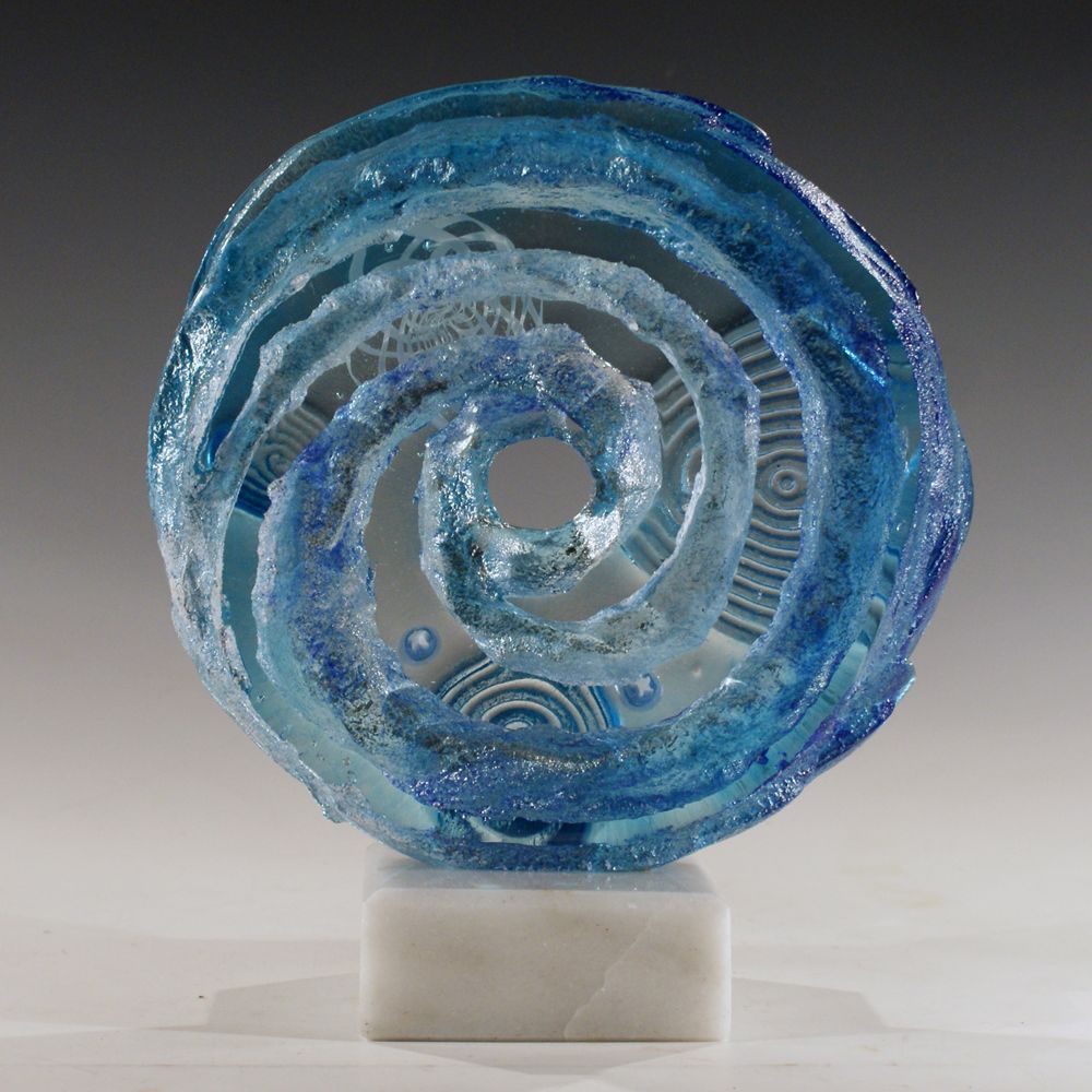 A blue glass sculpture with a spiral design sits on a white base