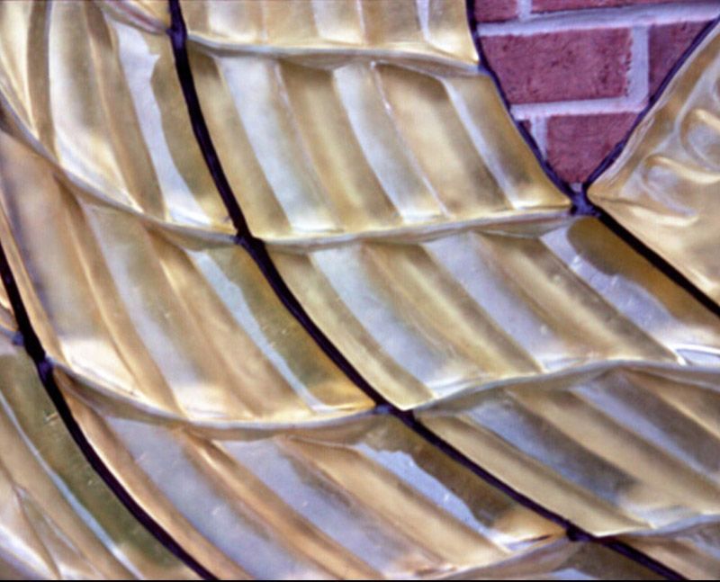 A close up of a gold plate with a brick wall in the background