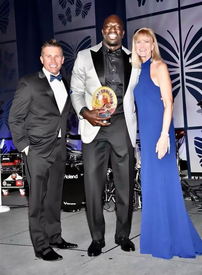 A man in a tuxedo and a woman in a blue dress pose for a photo
