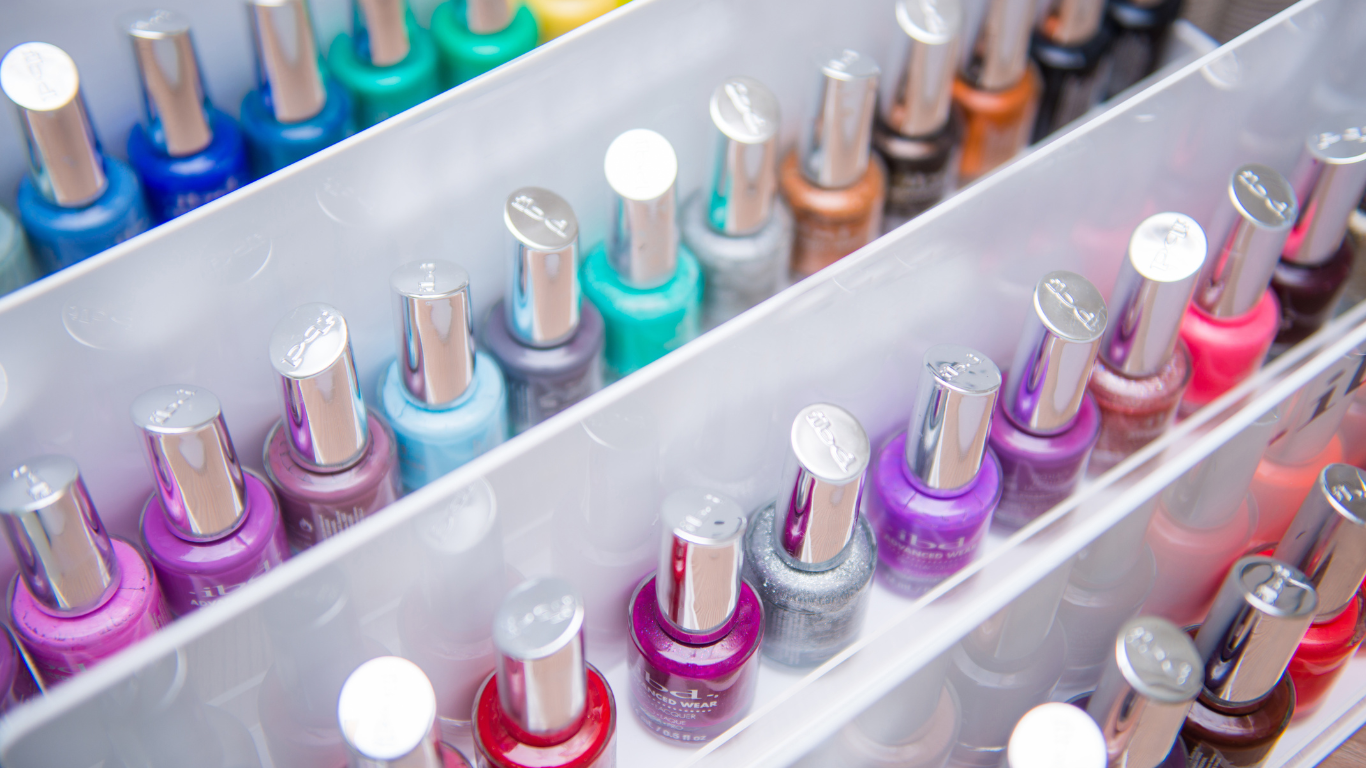 A shelf filled with bottles of nail polish of different colors.