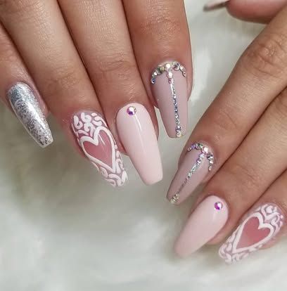 A close up of a woman 's nails with hearts and rhinestones.
