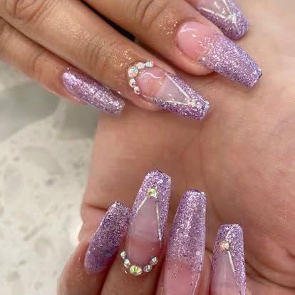 A close up of a person 's nails with purple glitter and rhinestones.
