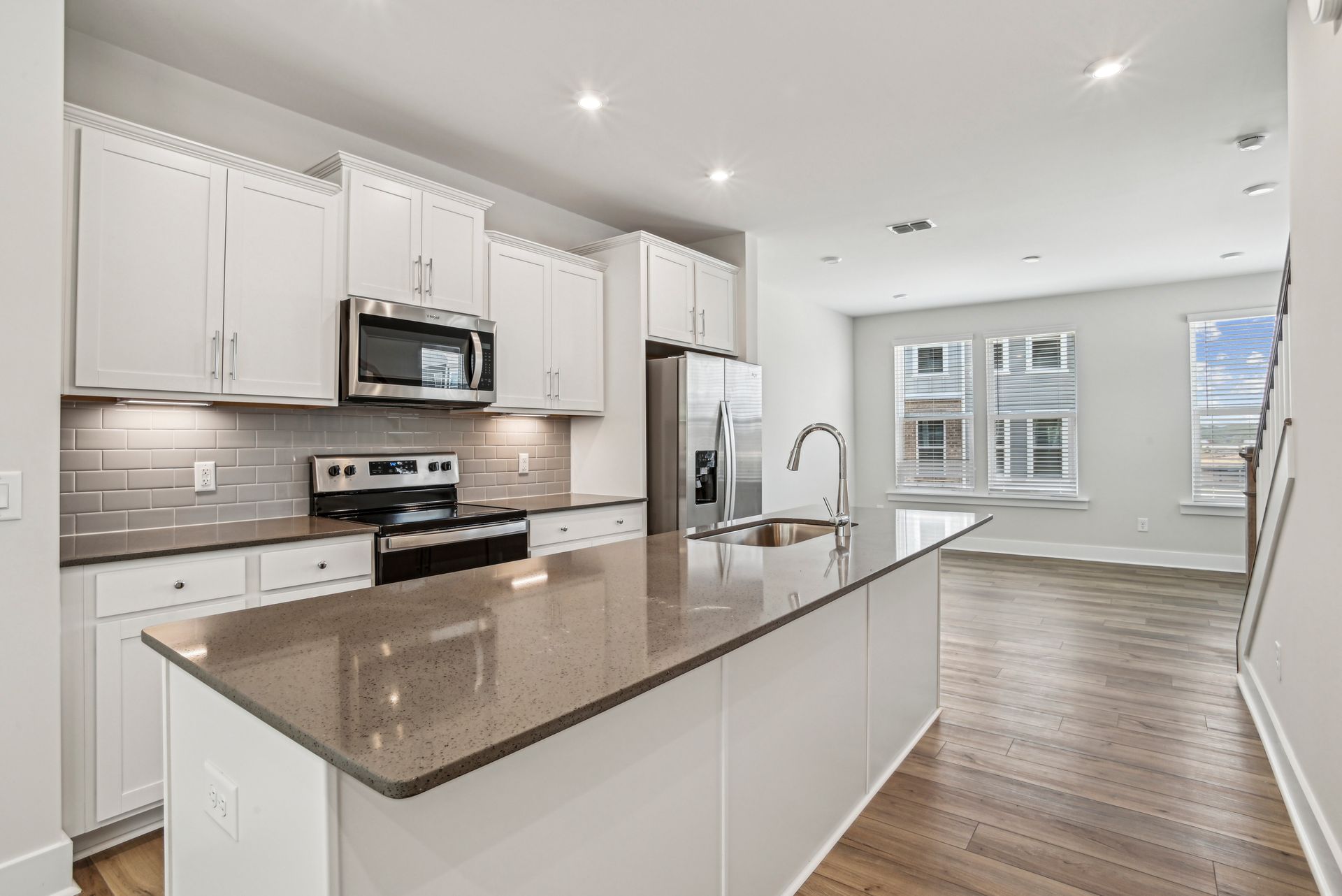 Modern kitchen with white cabinets, stainless steel appliances, and a large island.