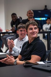 A group of young men are sitting at a table applauding.