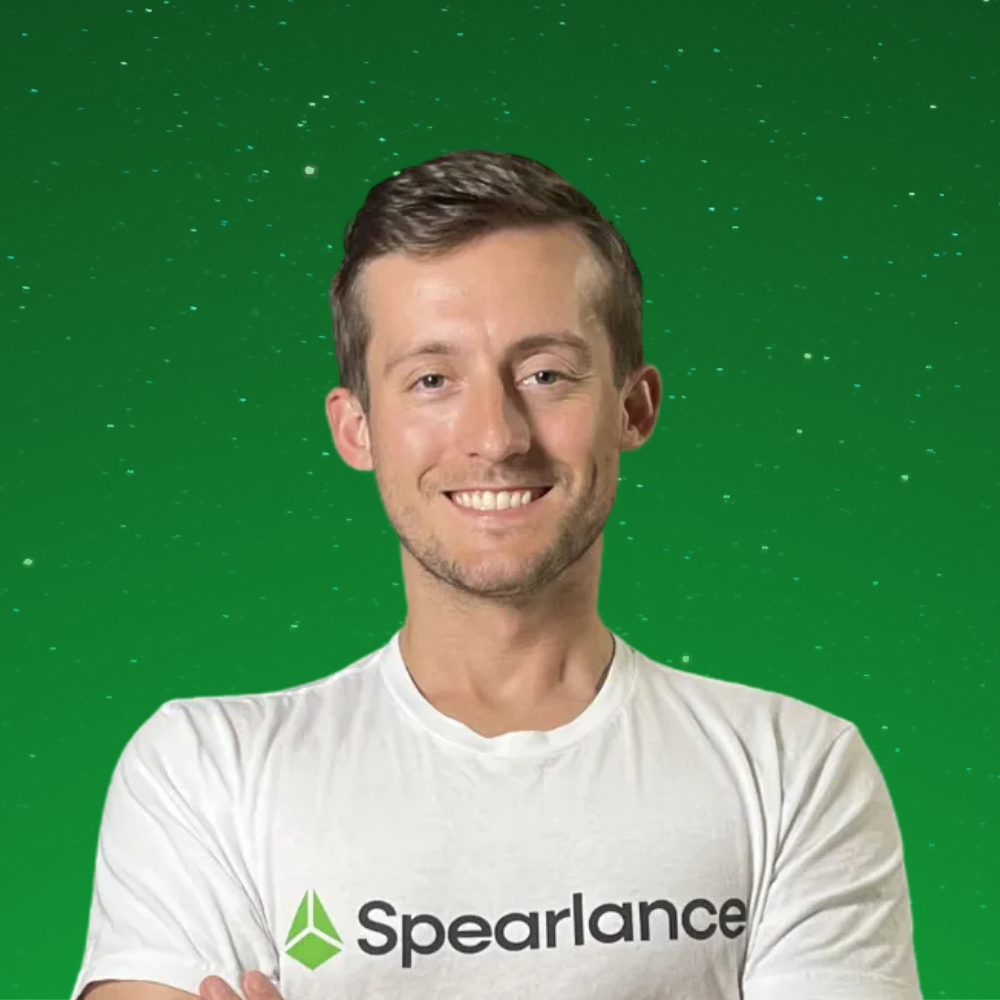 Smiling person in a white Spearlance shirt against a green background