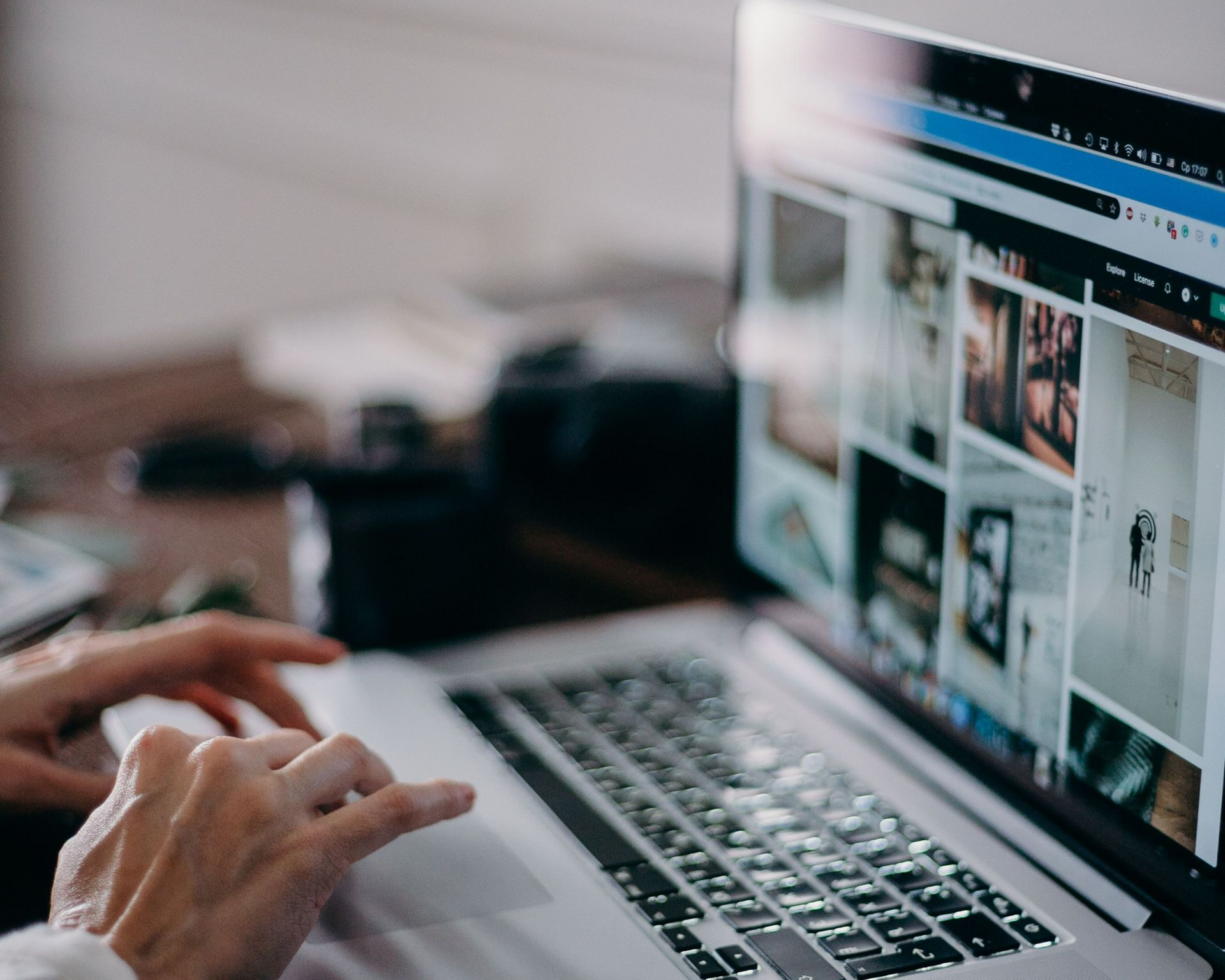 Hands typing on a laptop with a photo gallery open on screen
