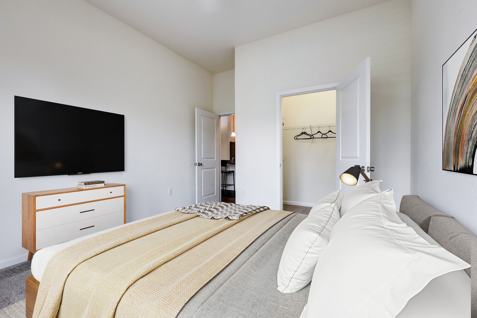 Bedroom with bed, dresser, TV, open closet, and artwork; neutral tones at Town Center at Lake Carolina in Columbia, SC.